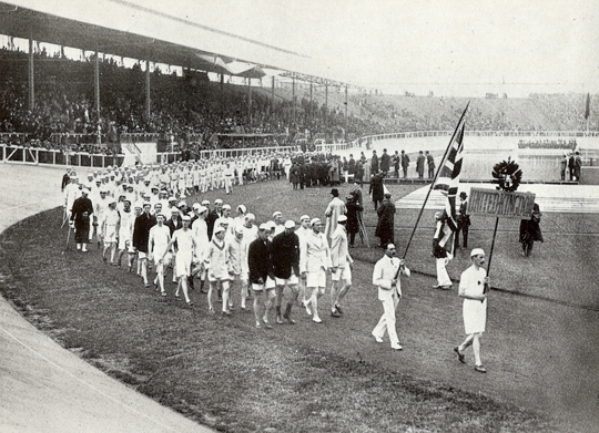 Photograph of Team GB in the opening ceremony's 'parade of nations,' from the Fourth Olympiad 1908 London. Official Report published by the <em></p>
<p id=